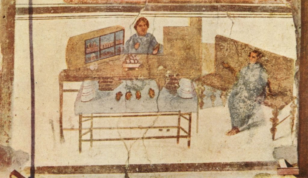 Fresco of felt shop of Verecundus. A man stands behind a counter with goods on display while another man sits on a bench gesturing as if talking to the first man.