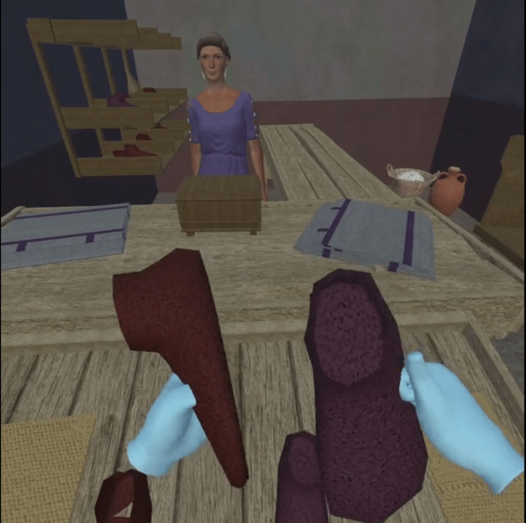 Screenshot from the virtual reconstruction of the felt shop of Verecundus. There is a first person view of the player holding red-brown felt shoes. Across the counter is the female shop keeper.